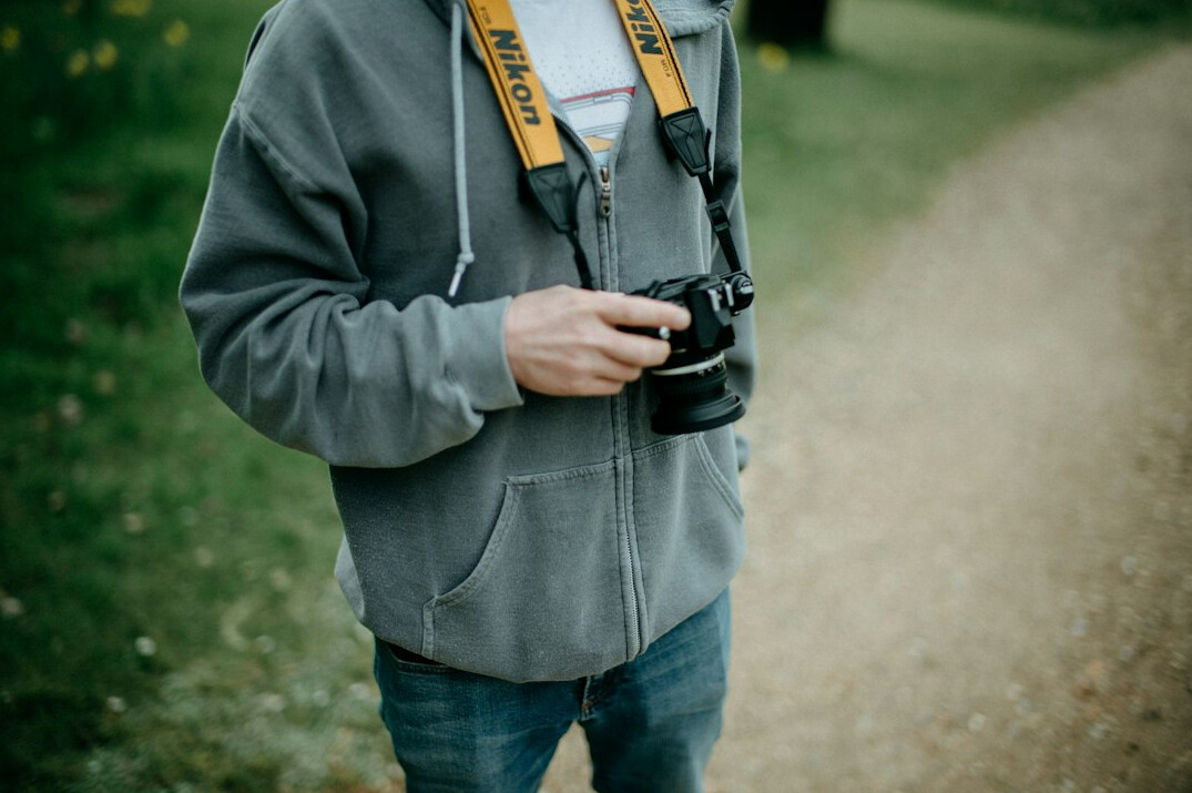Portrait of a Black British man in his thirties with a camera strap on his shoulder